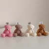 It looks like the image shows five teddy bear–shaped candles in different colors (purple, pink, light brown, cream, and medium brown) sitting in a row on a white surface. Each candle has a wick on top with a small tag that says "JE T'AIME CANDLE."