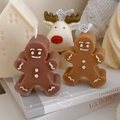Christmas candles surrounded by a gingerbread man and a reindeer, creating a festive holiday atmosphere.