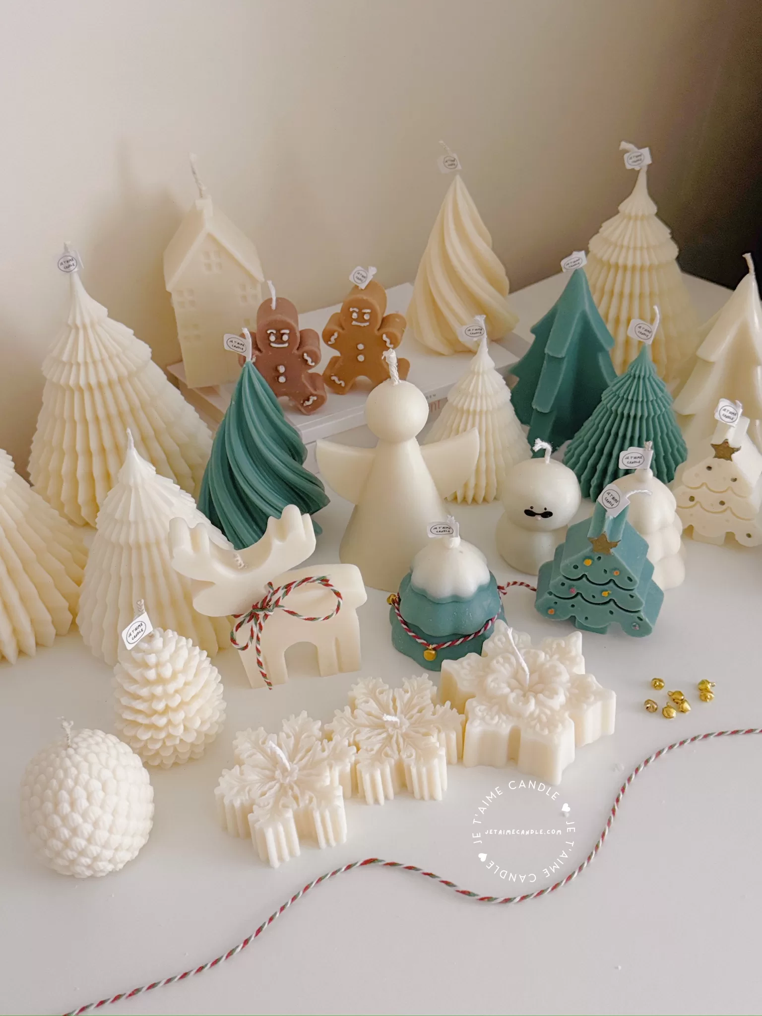 A table adorned with a variety of colorful Christmas decorations, including Christmas Tree Candles, Pinecone Shaped Candle, Angel Candle, Snowflake Christmas Candle, Town House Candle, Gingerbread Men Candle, Deer Candle.