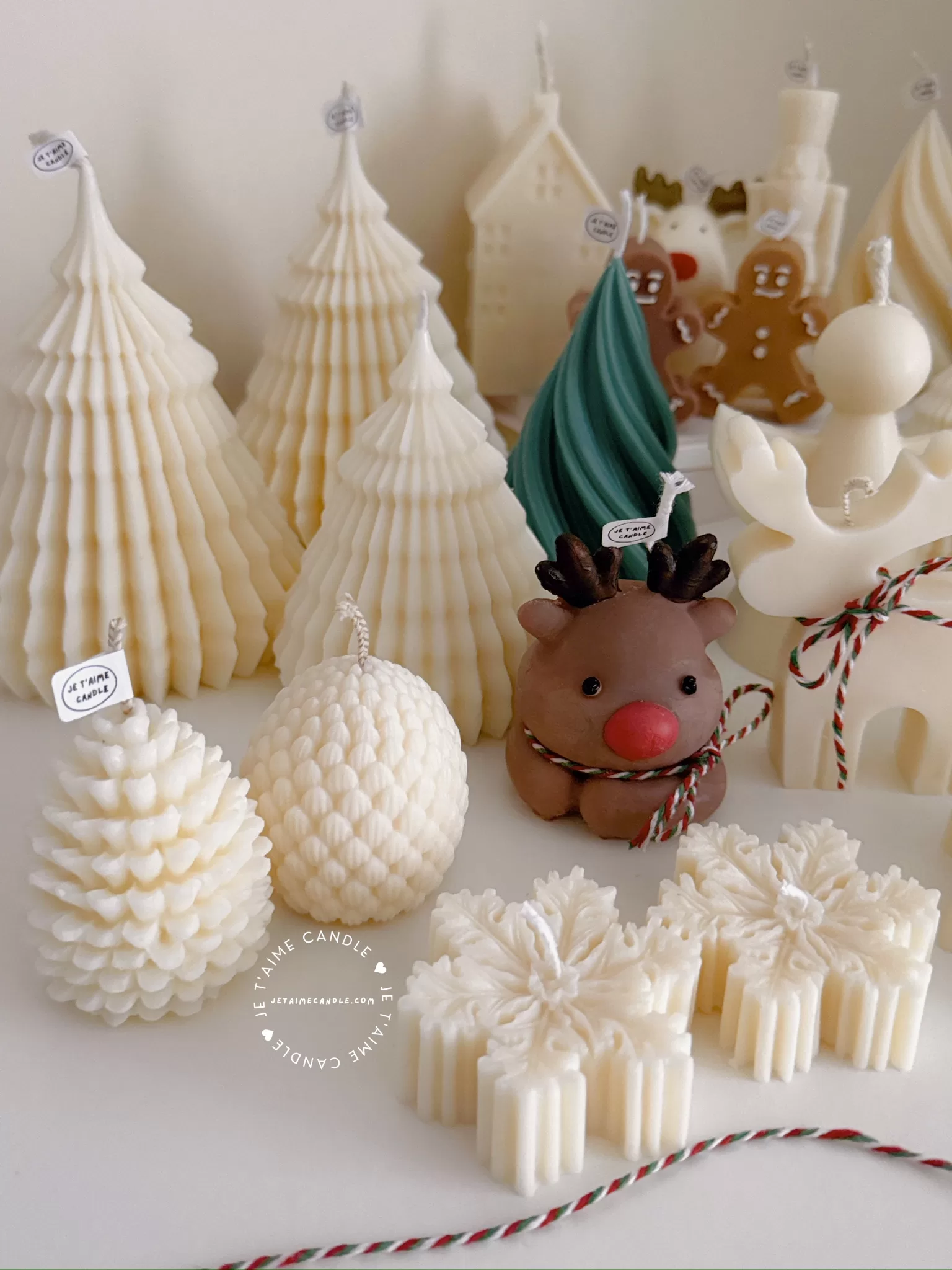 A table adorned with a variety of colorful Christmas decorations, including Christmas Tree Candles, Pinecone Shaped Candle, Angel Candle, Snowflake Christmas Candle, Town House Candle, Gingerbread Men Candle, Deer Candle.