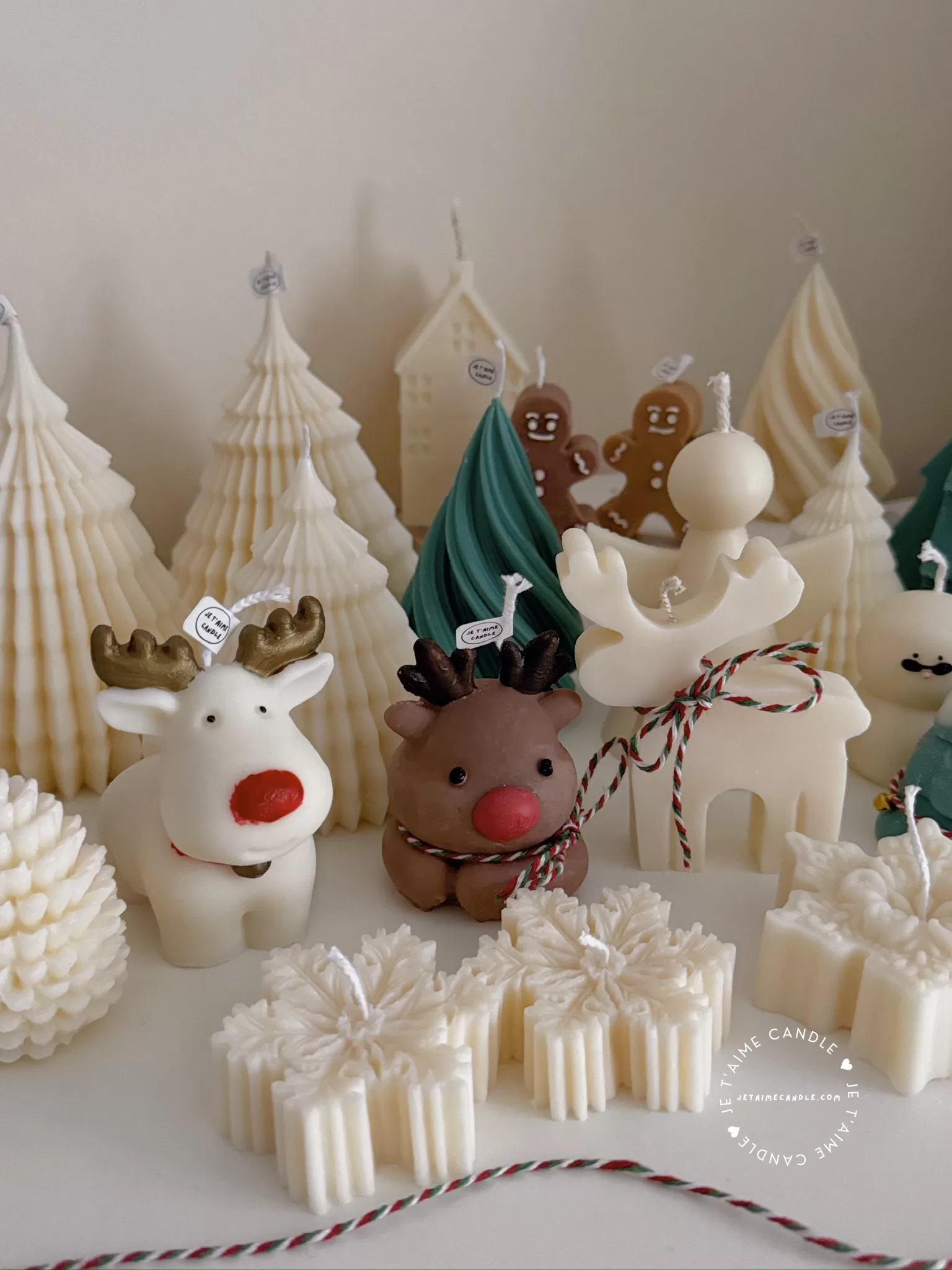 A table adorned with a variety of colorful Christmas decorations, including Christmas Tree Candles, Pinecone Shaped Candle, Angel Candle, Snowflake Christmas Candle, Town House Candle, Gingerbread Men Candle, Deer Candle.