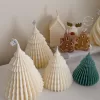 Four tree-shaped candles in cream and green colors are displayed in the foreground, with house, reindeer, and gingerbread man candles in the background.