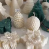 A table adorned with a variety of colorful Christmas decorations, including Christmas Tree Candles, Pinecone Shaped Candle, Angel Candle, Snowflake Christmas Candle, Town House Candle, Gingerbread Men Candle, Deer Candle.