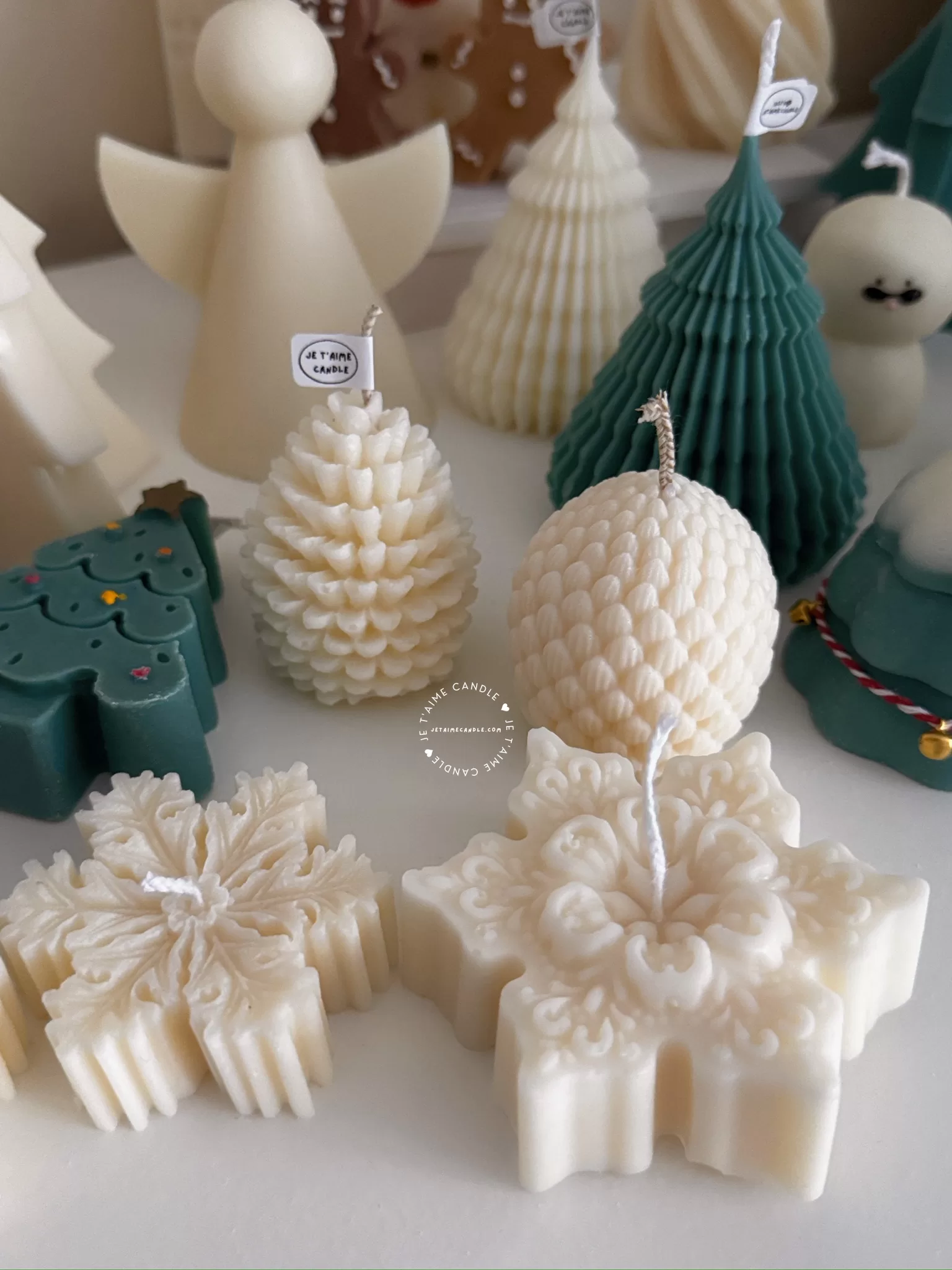 A table adorned with a variety of colorful Christmas decorations, including Christmas Tree Candles, Pinecone Shaped Candle, Angel Candle, Snowflake Christmas Candle, Town House Candle, Gingerbread Men Candle, Deer Candle.