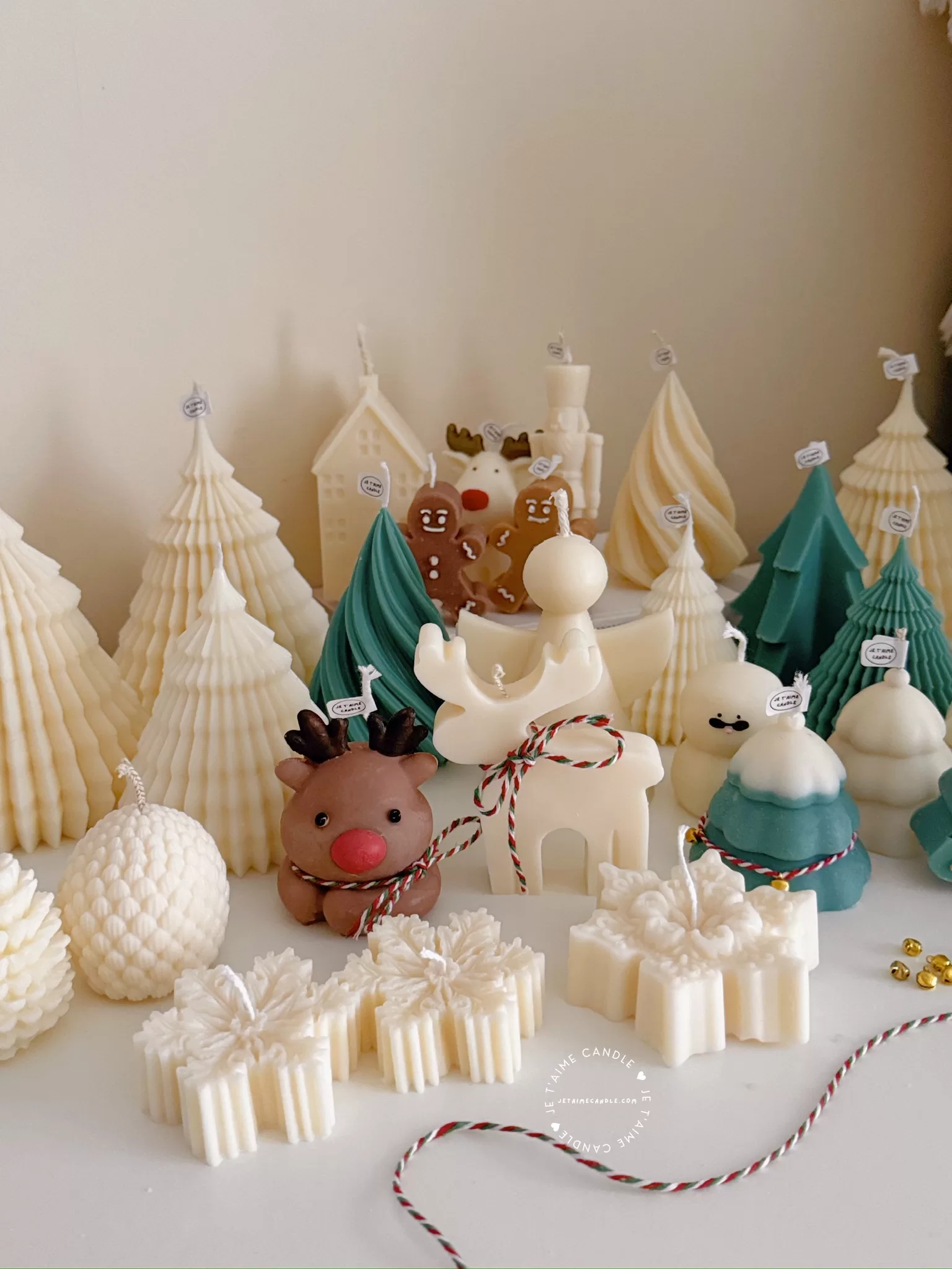 A table adorned with a variety of colorful Christmas decorations, including Christmas Tree Candles, Pinecone Shaped Candle, Angel Candle, Snowflake Christmas Candle, Town House Candle, Gingerbread Men Candle, Deer Candle.