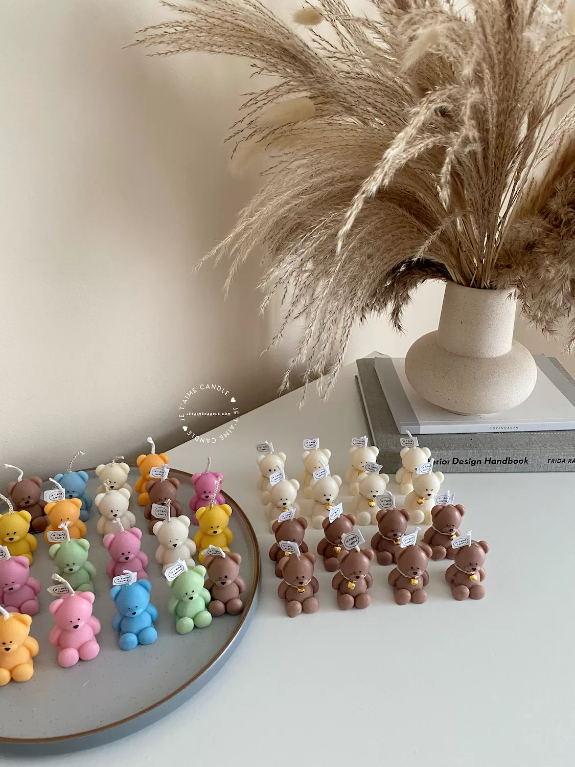 Handmade teddy bear candles in brown and cream colors, decorated with festive collars and golden bells, labeled "JE T’AIME CANDLE" – perfect for gifts, parties, and home decor