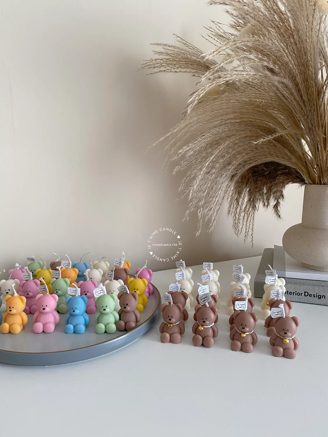 Handmade teddy bear candles in brown and cream colors, decorated with festive collars and golden bells, labeled "JE T’AIME CANDLE" – perfect for gifts, parties, and home decor