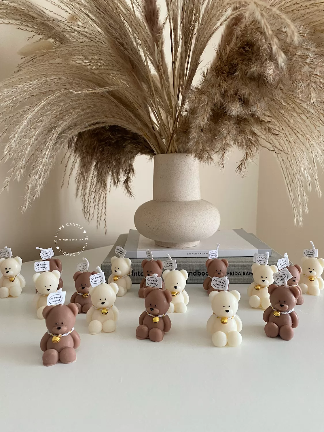 Handmade teddy bear candles in brown and cream colors, decorated with festive collars and golden bells, labeled "JE T’AIME CANDLE" – perfect for gifts, parties, and home decor