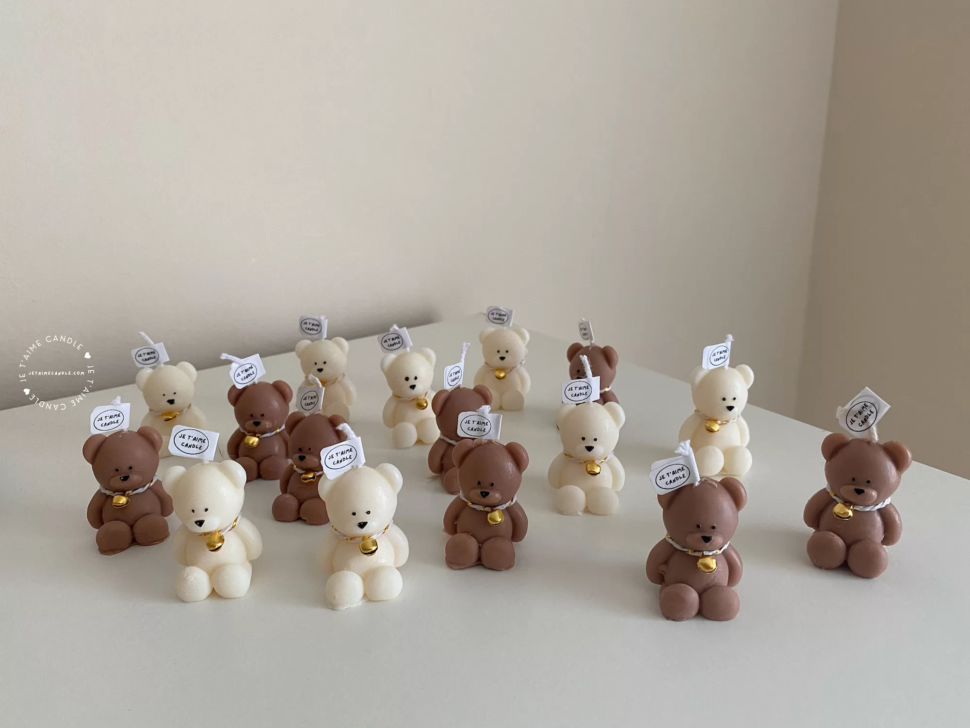 Handmade teddy bear candles in brown and cream colors, decorated with festive collars and golden bells, labeled "JE T’AIME CANDLE" – perfect for gifts, parties, and home decor