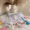 Colorful rose candles in pink, blue, yellow, and white, wrapped in white organza bags with personalized 'Thank You' tags for Amy's baby shower on 12/01/2024, displayed with pampas grass decor in the background