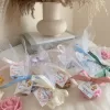 Colorful rose candles in pink, blue, yellow, and white, wrapped in white organza bags with personalized 'Thank You' tags for Amy's baby shower on 12/01/2024, displayed with pampas grass decor in the background