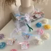Colorful rose candles in pink, blue, yellow, and white, wrapped in white organza bags with personalized 'Thank You' tags for Amy's baby shower on 12/01/2024, displayed with pampas grass decor in the background