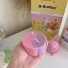 Four pastel yin-yang shaped candles in pairs of pink and purple, yellow and blue, green and cream, displayed on a white surface with a pink polka-dotted felt ball, a butter-themed box, and a disco ball nearby.
