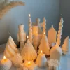 Set of white decorative candles shaped like Christmas trees, nutcrackers, angel, pinecones, and snowflakes, elegant holiday decor and gift.