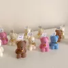 Adorable mini teddy bear candles in cream, pink, blue and brown with gold bell charms, displayed on a white table. Perfect baby shower favors, gender reveal party gifts, or cute keepsakes for guests.