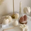 Assorted handmade Christmas candles in festive shapes including Pinecone, snowflakes, taper candle, displayed together in holiday-themed colors.