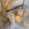 Two handmade ribbed pillar candles in ivory white soy wax, one tall and one short, placed on a white stone base beside pampas grass, a gold candle holder, and decorative candles. The ribbed texture gives these candles a modern minimalist look, making them ideal for wedding centerpieces, cozy home décor, or as stylish handmade gifts. Their clean design and neutral color make them versatile decorative accents that fit perfectly into Scandinavian, modern, and rustic interiors.