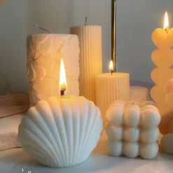 Handmade soy wax decorative candles in creamy white, including ribbed pillar, bubble cube, spiral twist, heart-shaped, bear-shaped, and swirl ball designs, lit for cozy aesthetic home décor, wedding table decoration, or unique gift ideas.