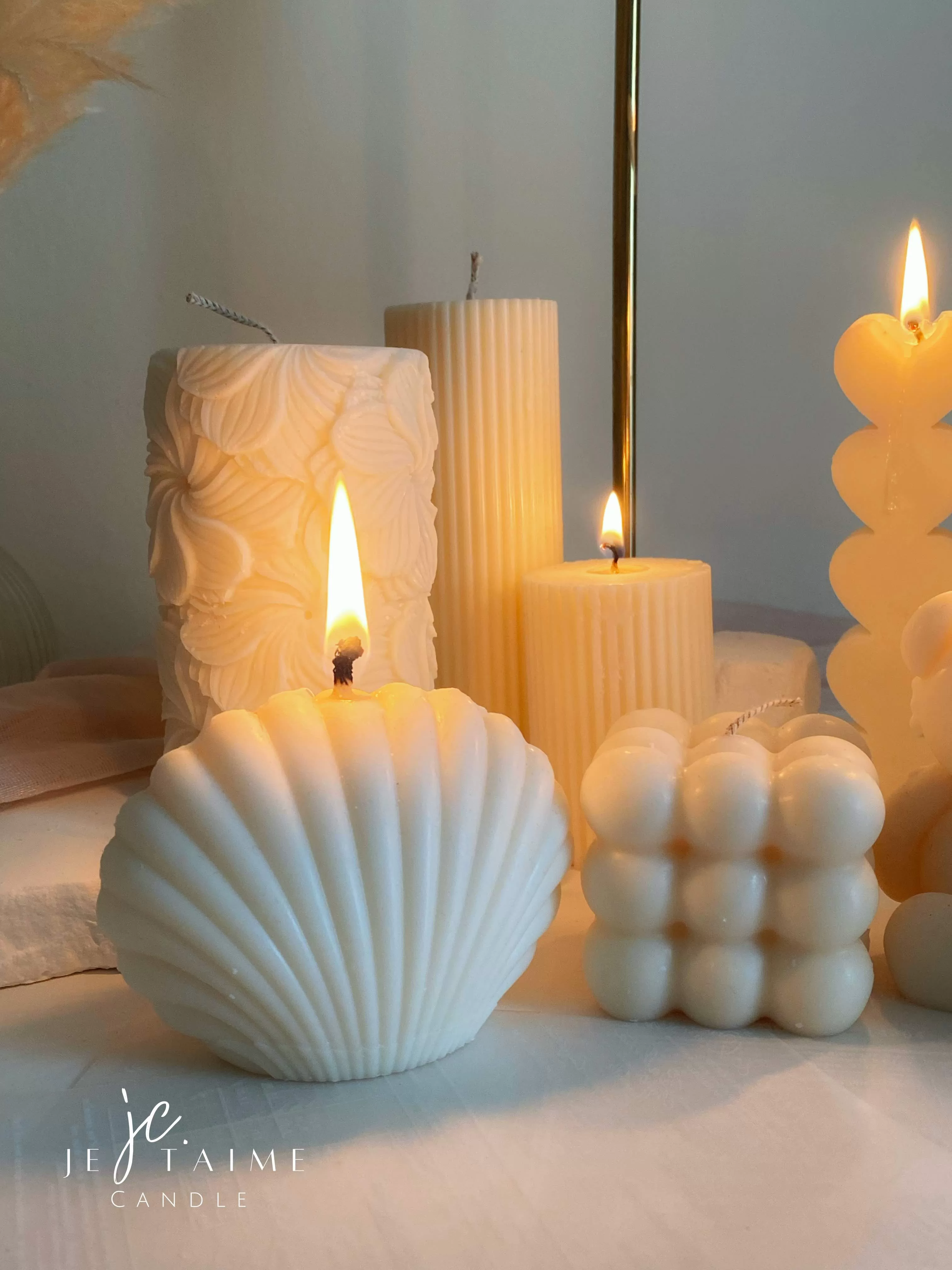 Handmade soy wax decorative candles in creamy white, including ribbed pillar, bubble cube, spiral twist, heart-shaped, bear-shaped, and swirl ball designs, lit for cozy aesthetic home décor, wedding table decoration, or unique gift ideas.