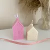 Two pink house-shaped candles on a table, perfect for housewarming gifts and cozy home decor.
