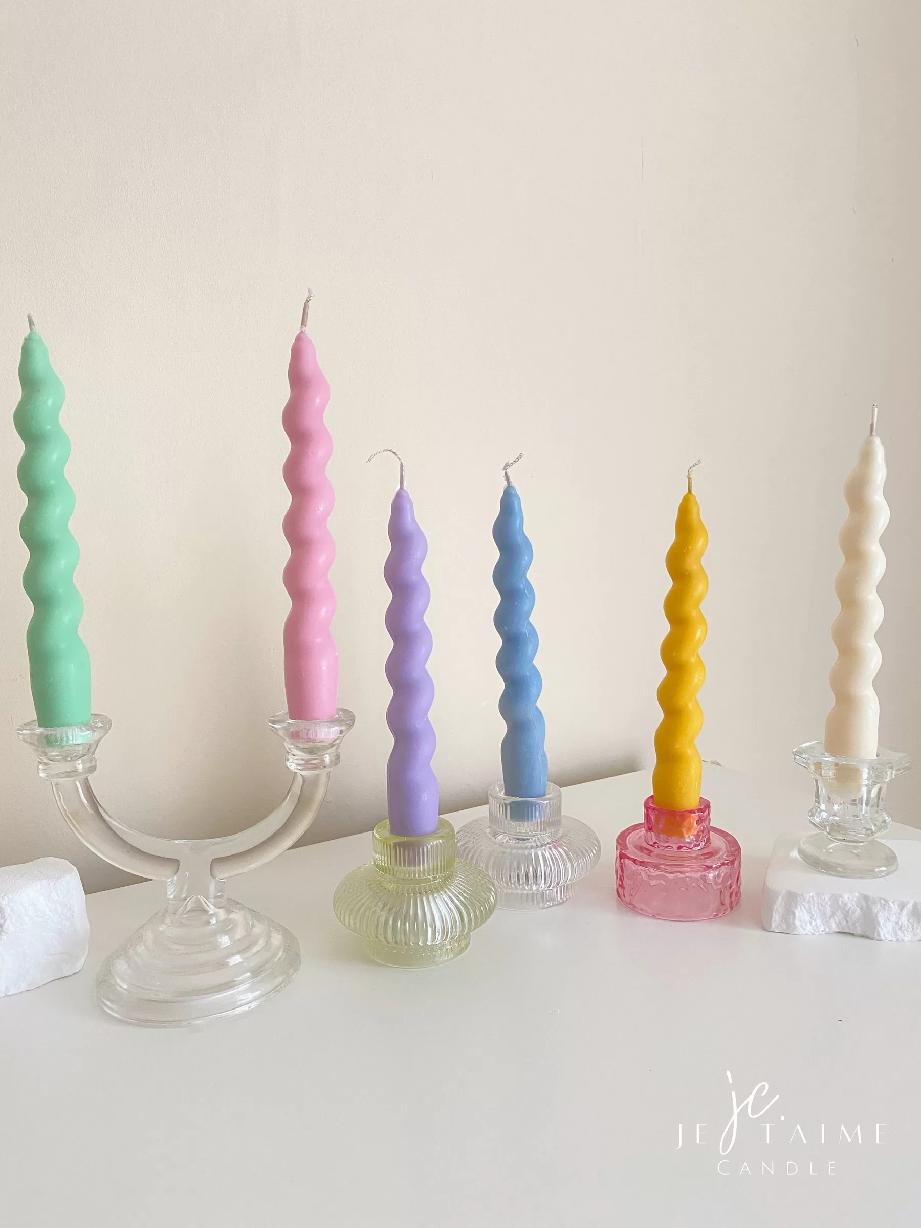 Set of colorful spiral twist soy wax taper candles in pastel green, pink, lavender, blue, yellow, and cream, displayed in clear glass holders, perfect for dinner table decor, wedding centerpieces, and modern home styling.