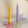 Set of colorful spiral twist soy wax taper candles in pastel yellow and purple, displayed in clear glass holders, perfect for dinner table decor, wedding centerpieces, and modern home styling.