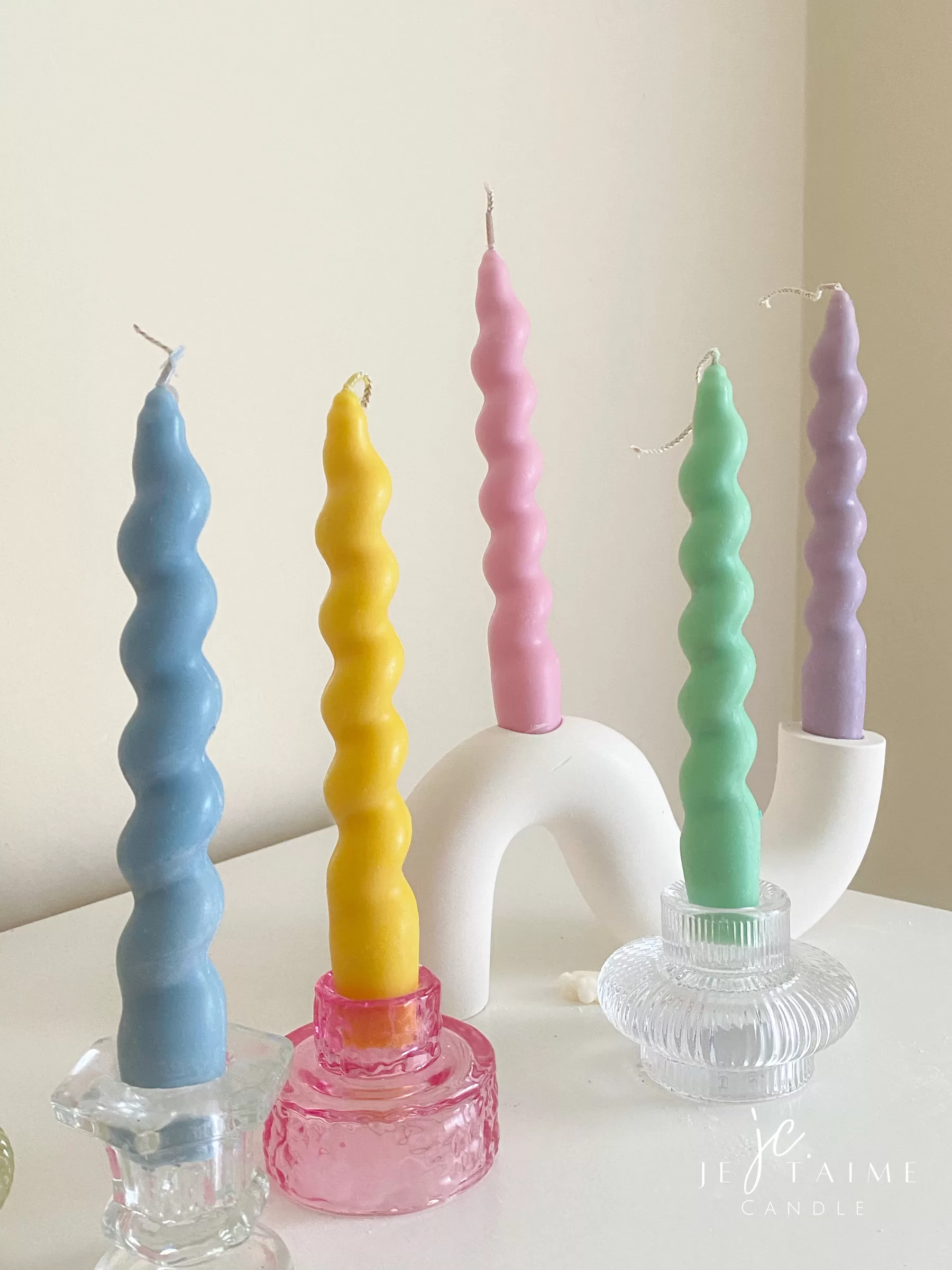 Set of colorful spiral twist soy wax taper candles in pastel green, pink, lavender, blue, yellow, and cream, displayed in clear glass holders, perfect for dinner table decor, wedding centerpieces, and modern home styling.