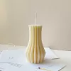 Handmade vase column aesthetic candle in ivory soy wax with a modern fluted design, displayed on a white stone base with pampas grass and other decorative candles in the background. This sculptural column candle is perfect for minimalist home décor, wedding centerpieces, or as a unique handmade gift, adding timeless elegance and modern style to any space.