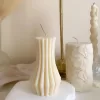 Handmade vase column aesthetic candle in ivory soy wax with a modern fluted design, displayed on a white stone base with pampas grass and other decorative candles in the background. This sculptural column candle is perfect for minimalist home décor, wedding centerpieces, or as a unique handmade gift, adding timeless elegance and modern style to any space.