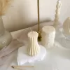 Handmade vase column aesthetic candle in ivory soy wax with a modern fluted design, displayed on a white stone base with pampas grass and other decorative candles in the background. This sculptural column candle is perfect for minimalist home décor, wedding centerpieces, or as a unique handmade gift, adding timeless elegance and modern style to any space.