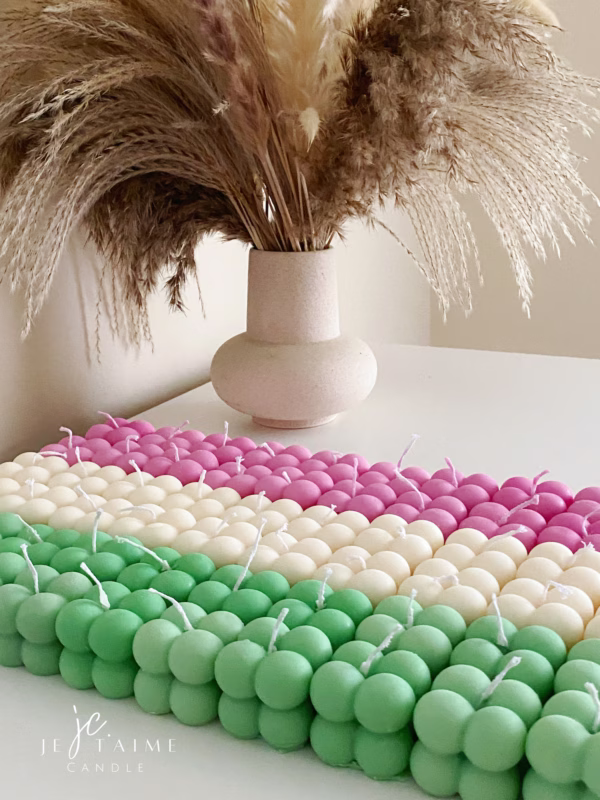 A collection of colorful candles labeled with personalized tags, alongside mini baby bubble candles for special events.